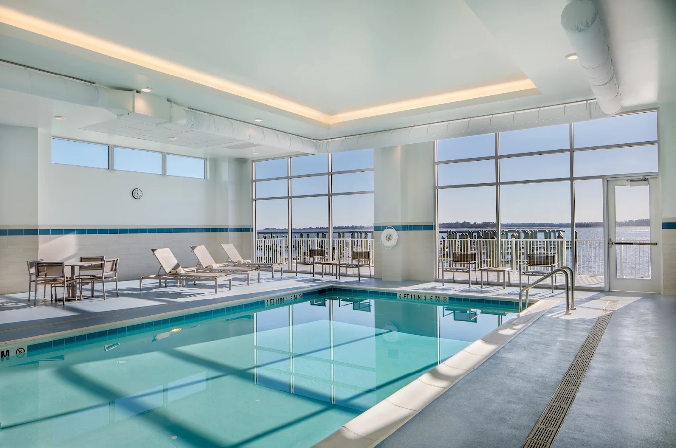 Indoor pool with floor-to-ceiling windows facing the water